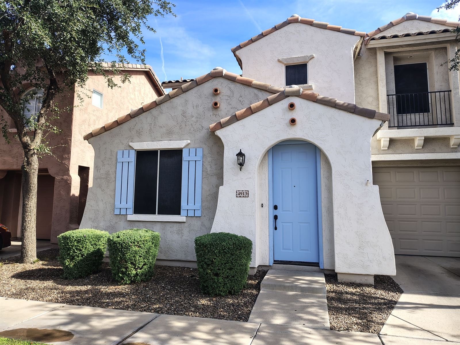 Freshly repainted stucco home exterior with a custom light-blue front door and matching shutters in Phoenix, Arizona